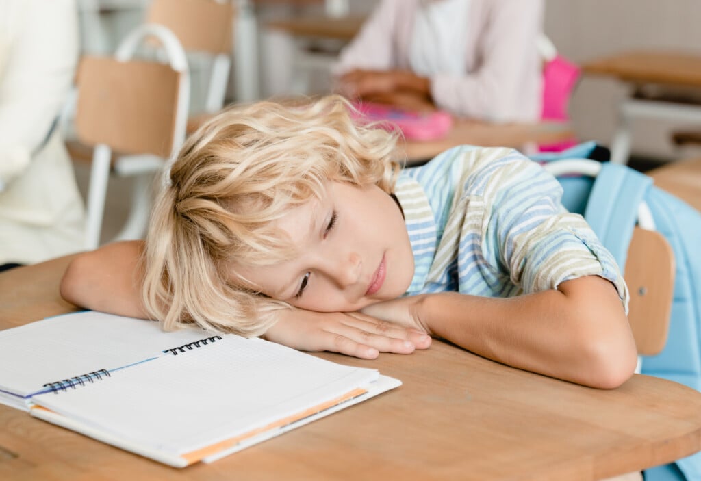 distracted boy at school with head on desk