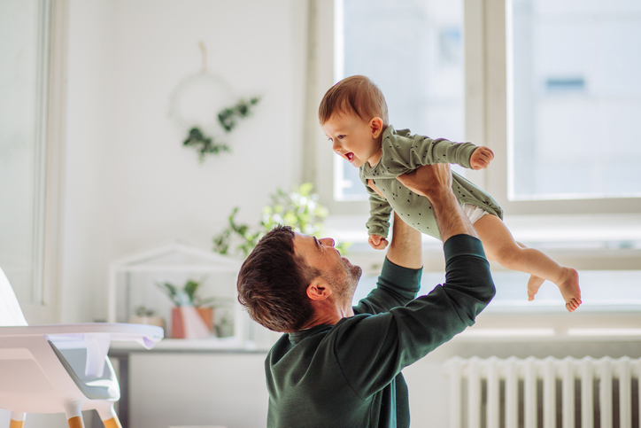 father playing with older baby