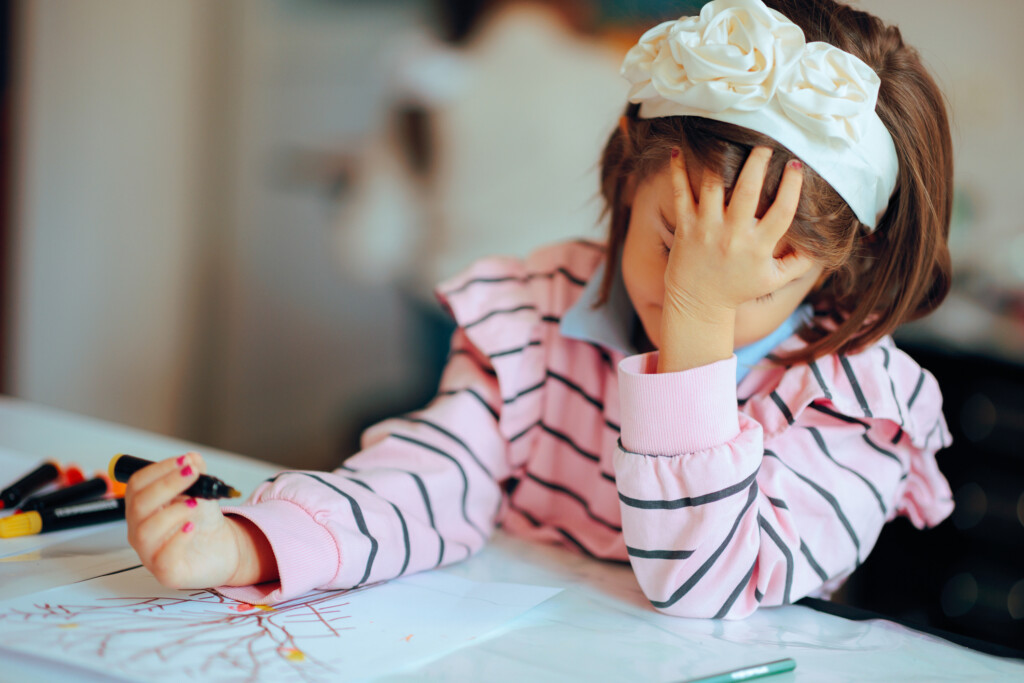 stressed out girl drawing in preschool classroom
