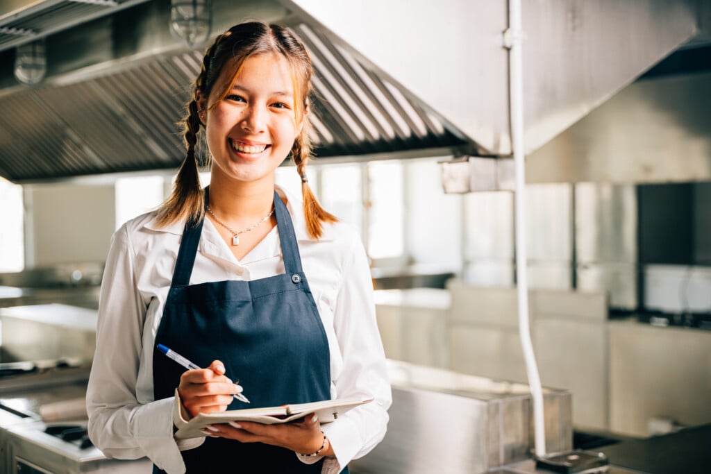 a high school student smiling in a commercial kitchen