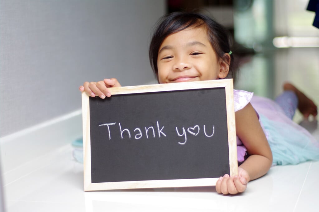 girl holding a thank you sign