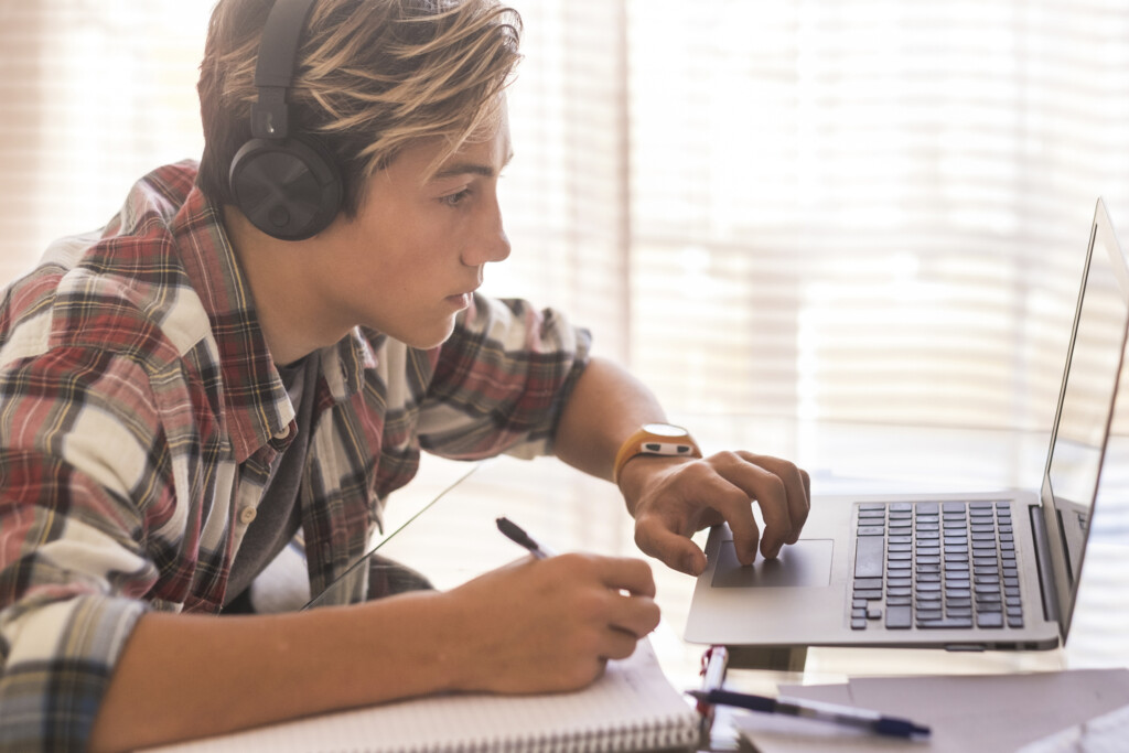 teen boy using laptop with headphones