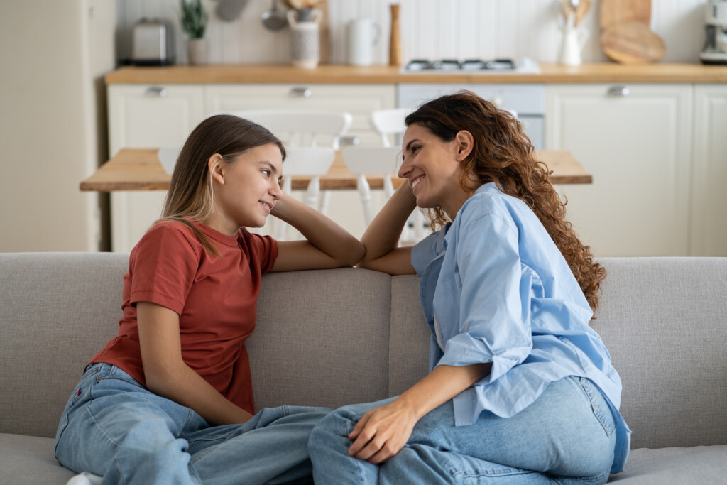 adult woman talking with teen on couch