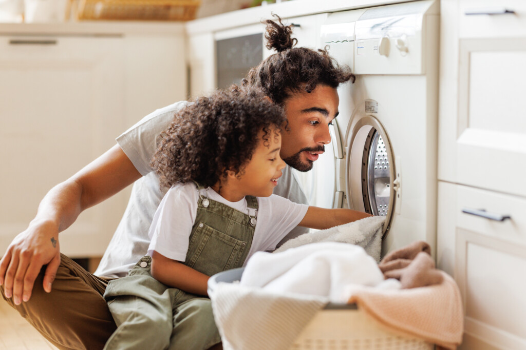 father and young boy looking at laundry machine