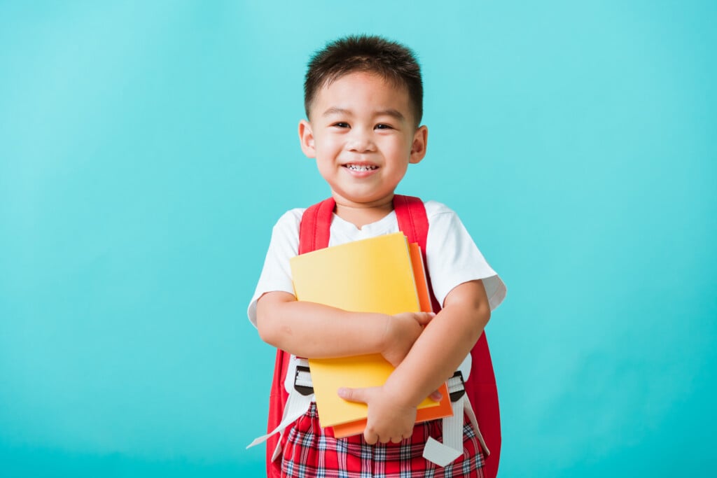 preschool-aged boy with backpack holding folders