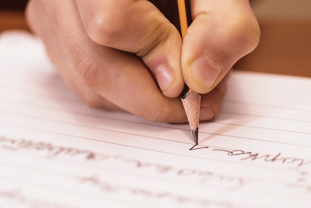 a hand writing cursive with a pencil
