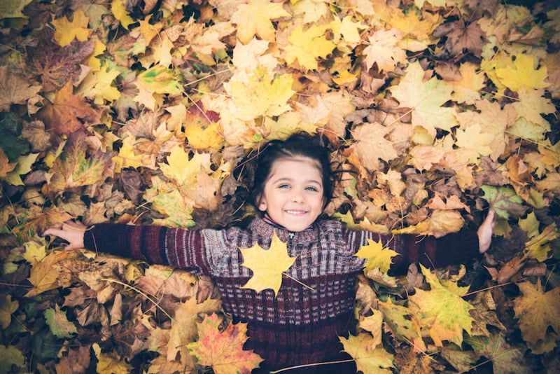 girl playing in leaves, for article on thanksgiving break in tulsa