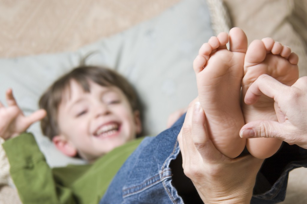 Young child with feet in the air. An adult hand is tickling the feet