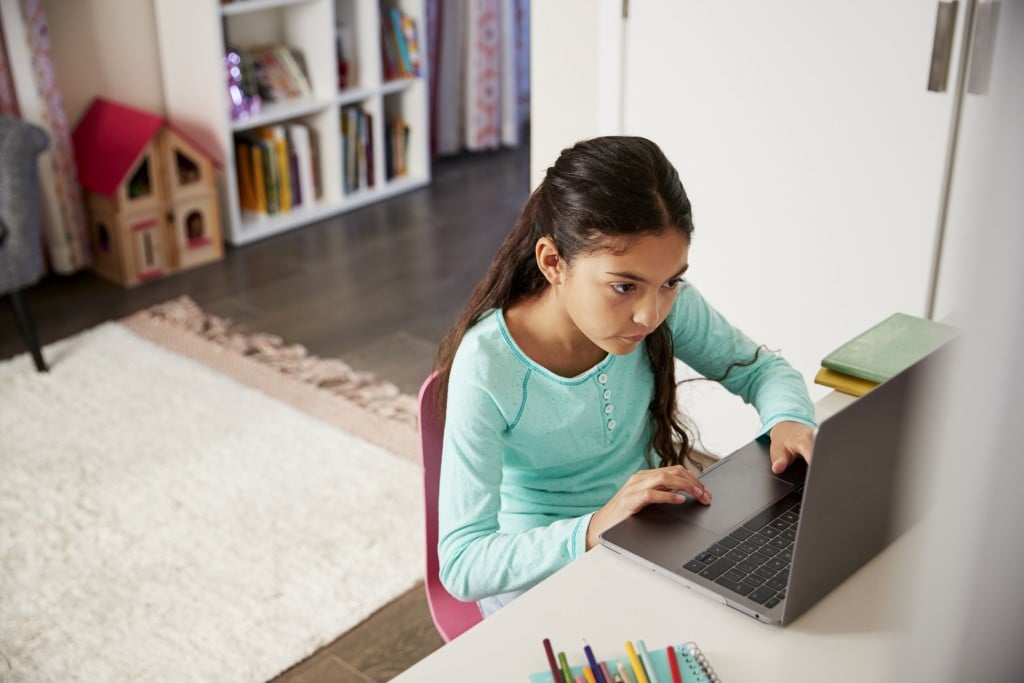 young girl at desk with laptop. chromebooks and kids concept