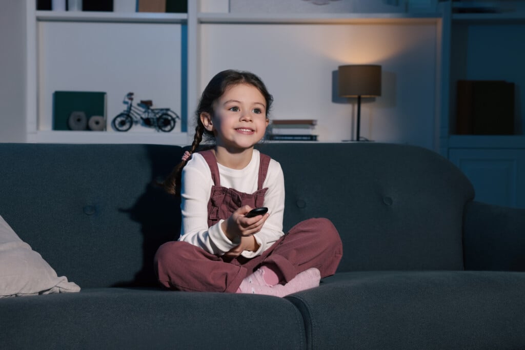 Happy Girl Changing Tv Channels With Remote Control On Sofa At Home