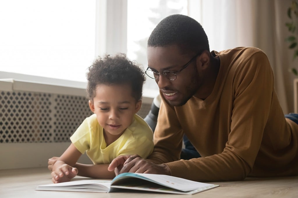 father helping young child read, for article on parents as teachers