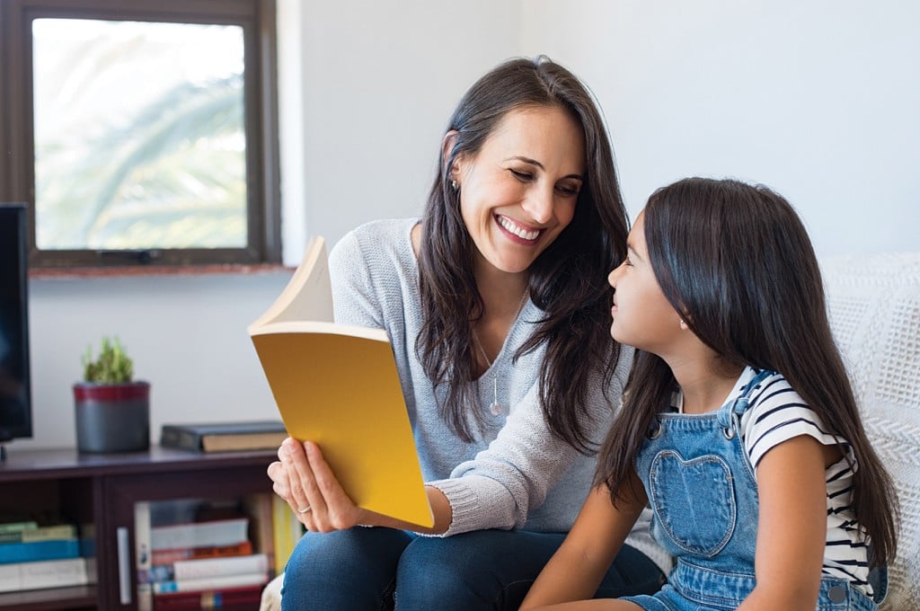mom reading book to daughter, for article on how to start homeschooling