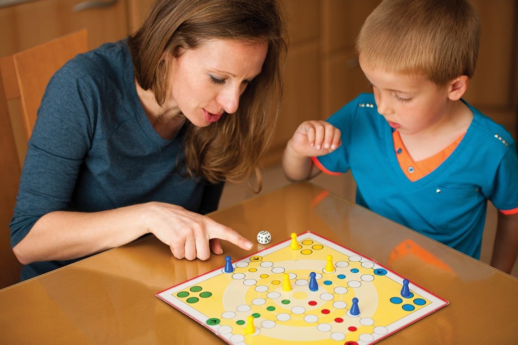 mom and child playing board game, for article on sibling rivalry