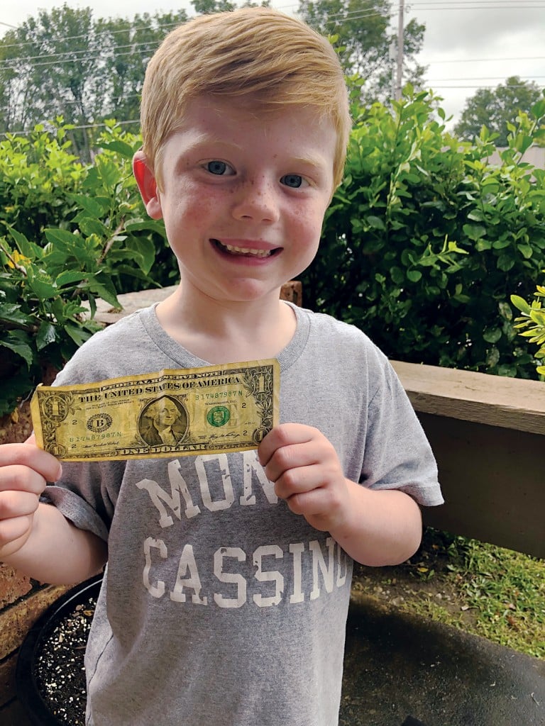 young boy holds a dollar bill. teaching children about money concept