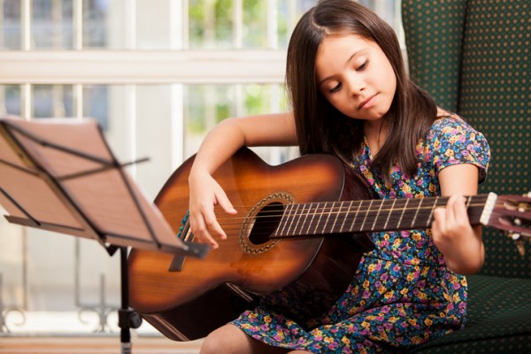 girl playing guitar, for article on skills to learn during the pandemic