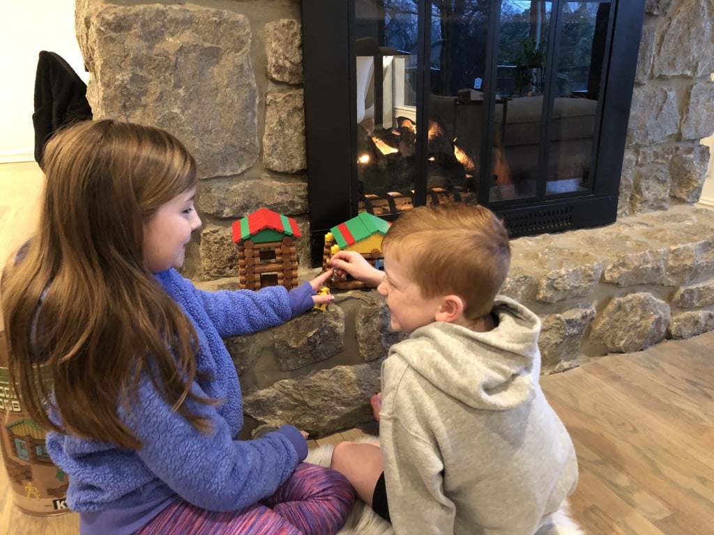 sister and brother playing together by fireplace, for article on independent play