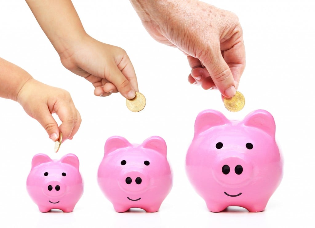 young hands putting coins into piggy banks, for article on giving kids allowance