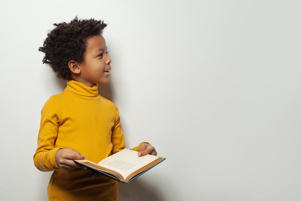 Curious Black Child Boy Reading A Book On White Background