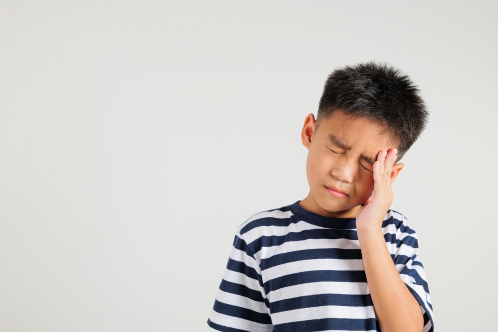 young boy sad and rubbing forehead