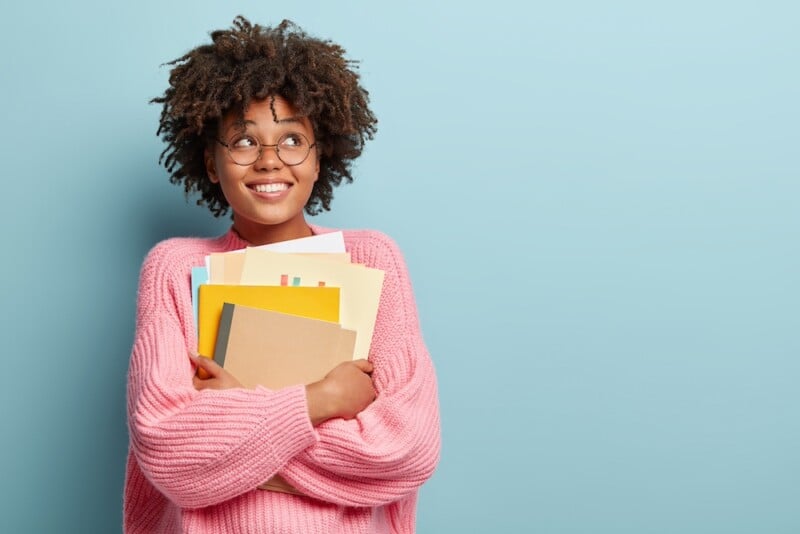 optimistic girl holding notebooks and looking up