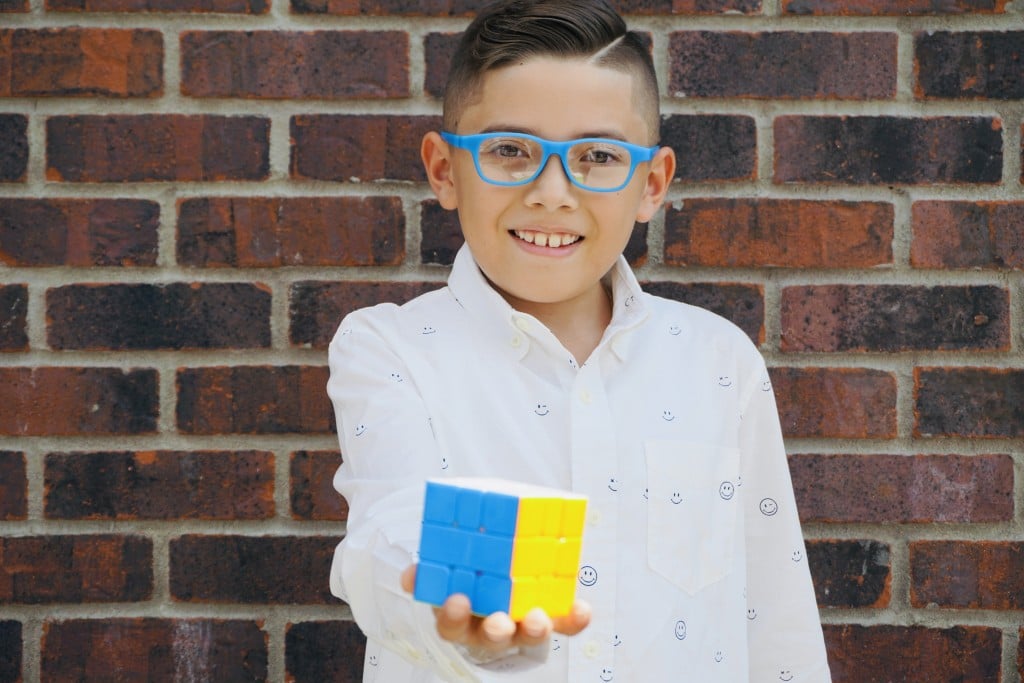 Fernando Robles Alvardo smiles and holds a completed Rubik's Cube