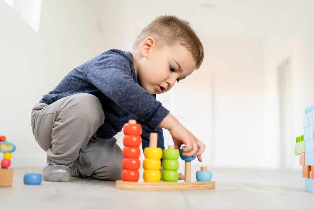 Small Boy Playing With Little Wood Toys At Home On The Floor Learning Colors And Counting