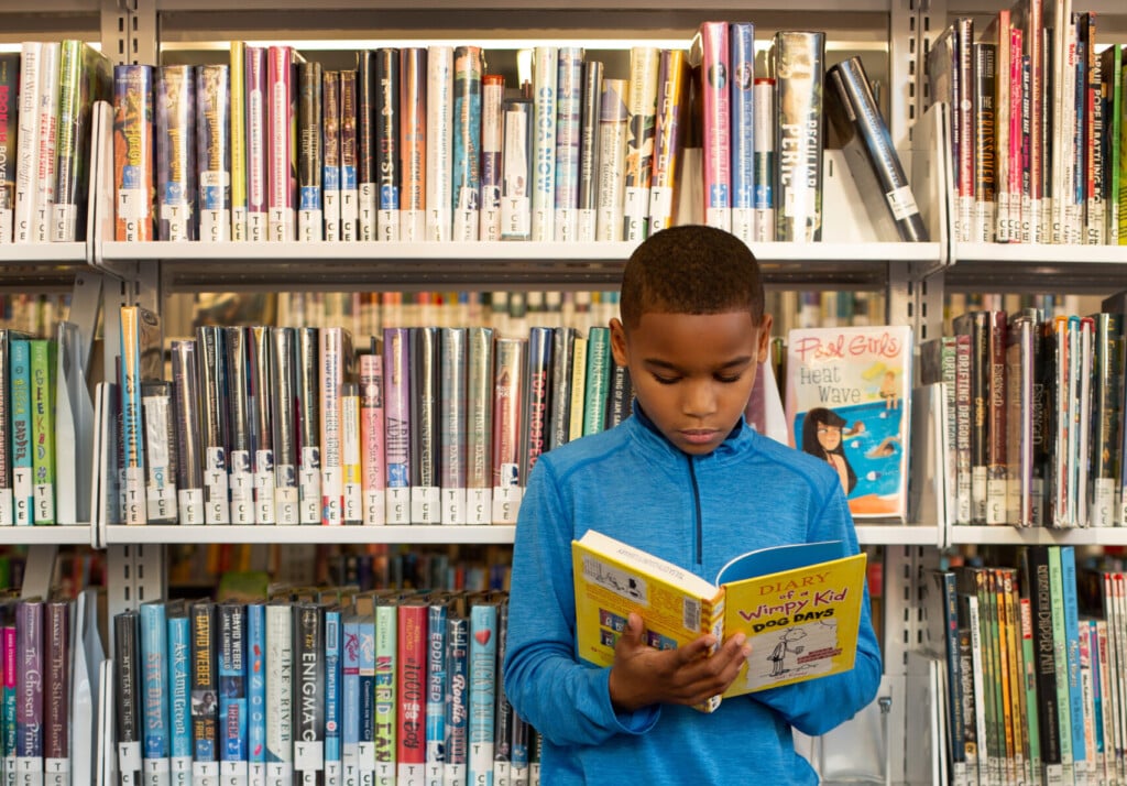 a school-age boy reading in a library