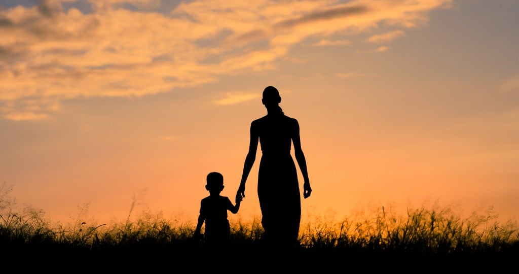 Mother And Son Holding Hands And Walking At Sunset