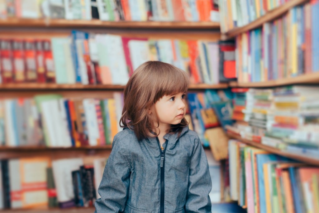 Happy Playful Toddler Girl Standing In A Library
