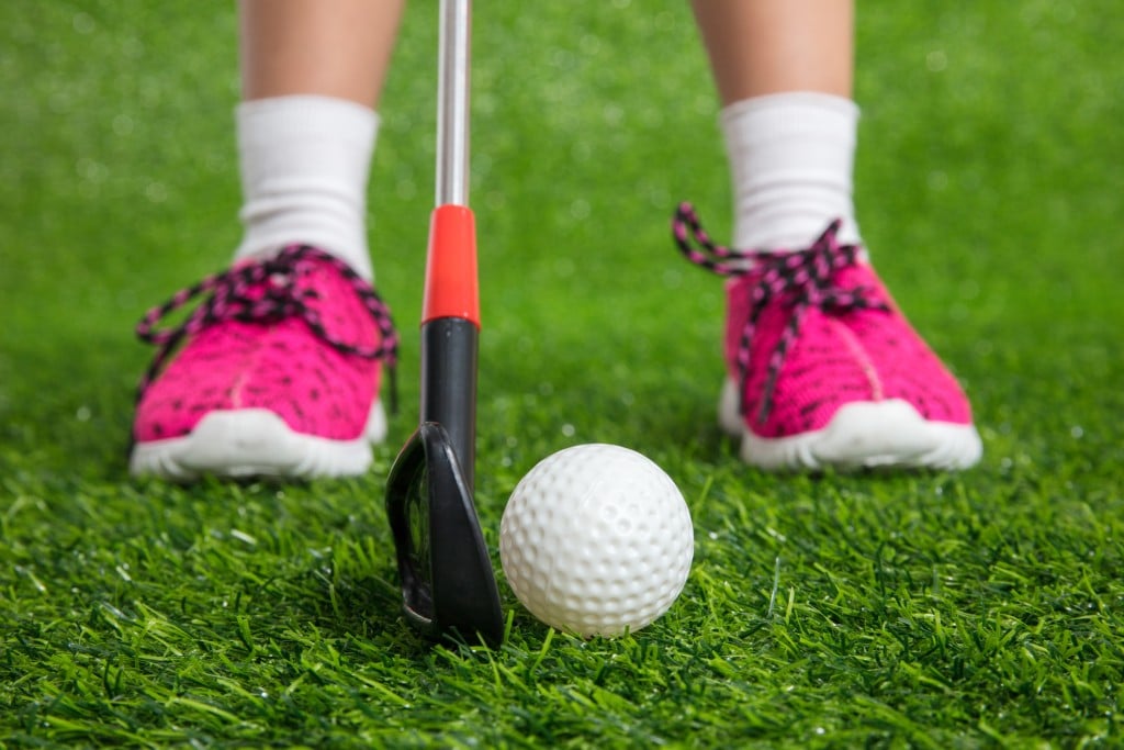 Closeup Of A Child Golfer With Putter And Ball