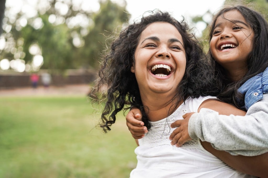 laughing mom giving daughter a piggyback ride, for article on mothers day in tulsa