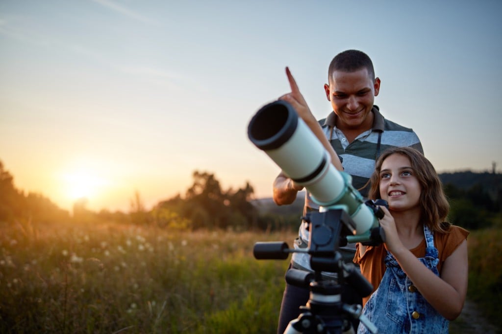 Father And Daughter Observing The Sky With A Telescope.