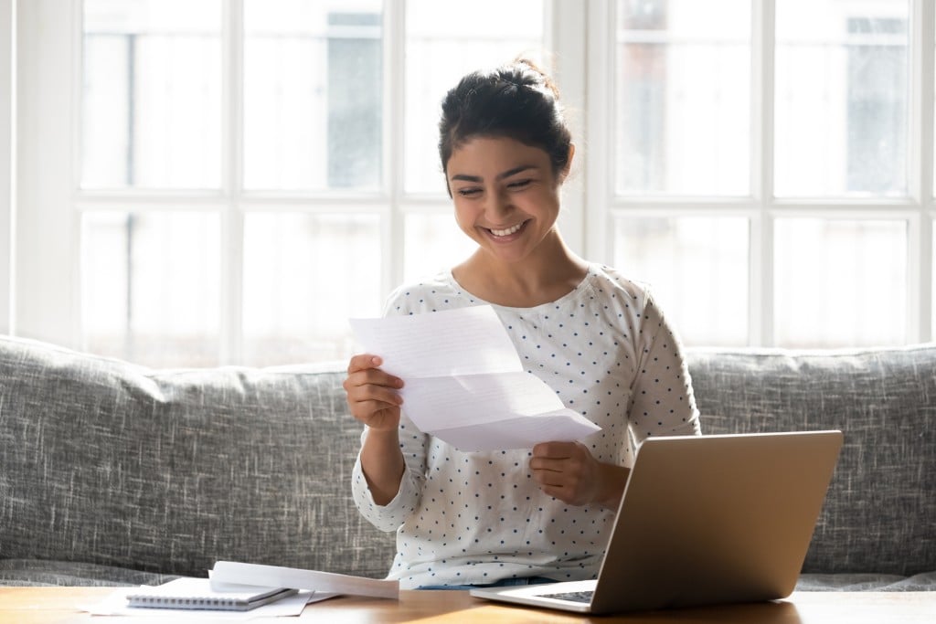 smiling college age woman holding letter, for article on college recommendation letters