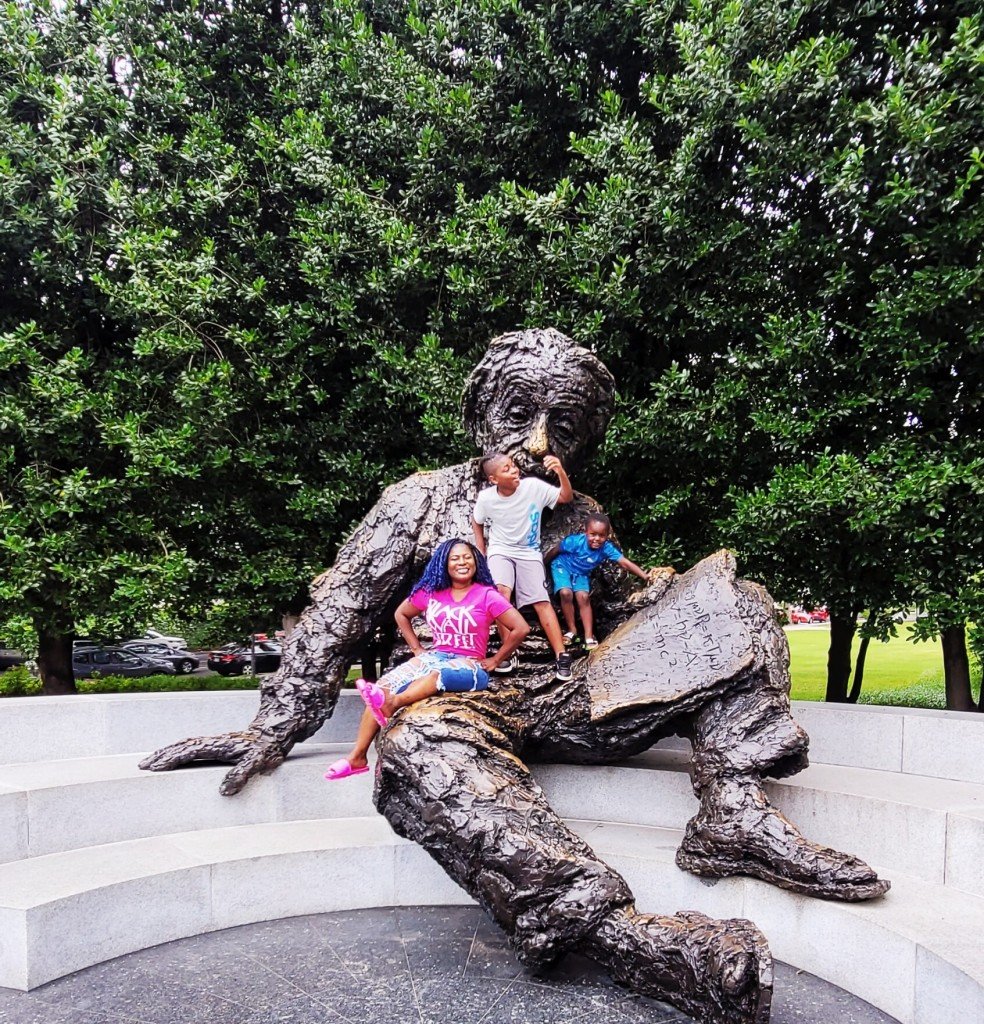dr tamecca and two of her sons on the albert einstein statue, for article on respectful parenting