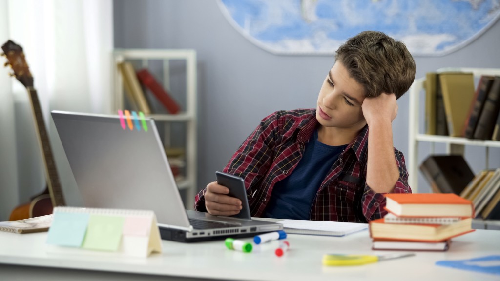 Bored male student distracted by phone while doing homework, for article on adhd