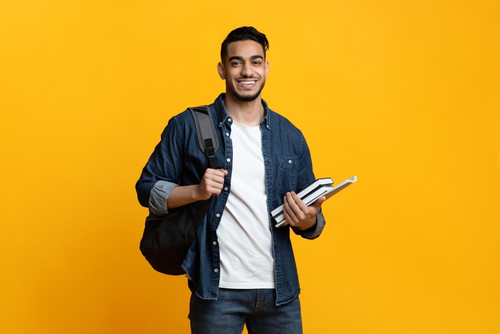 smiling male college student on yellow background