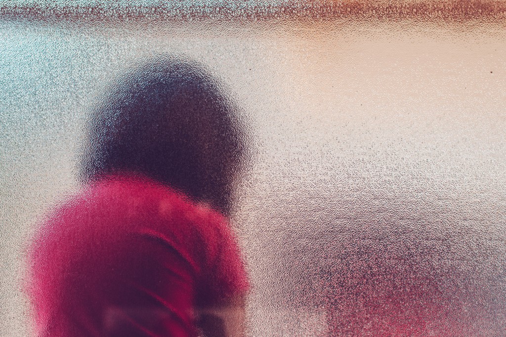 silhouette of sad girl behind stained glass, for article on sexual predators