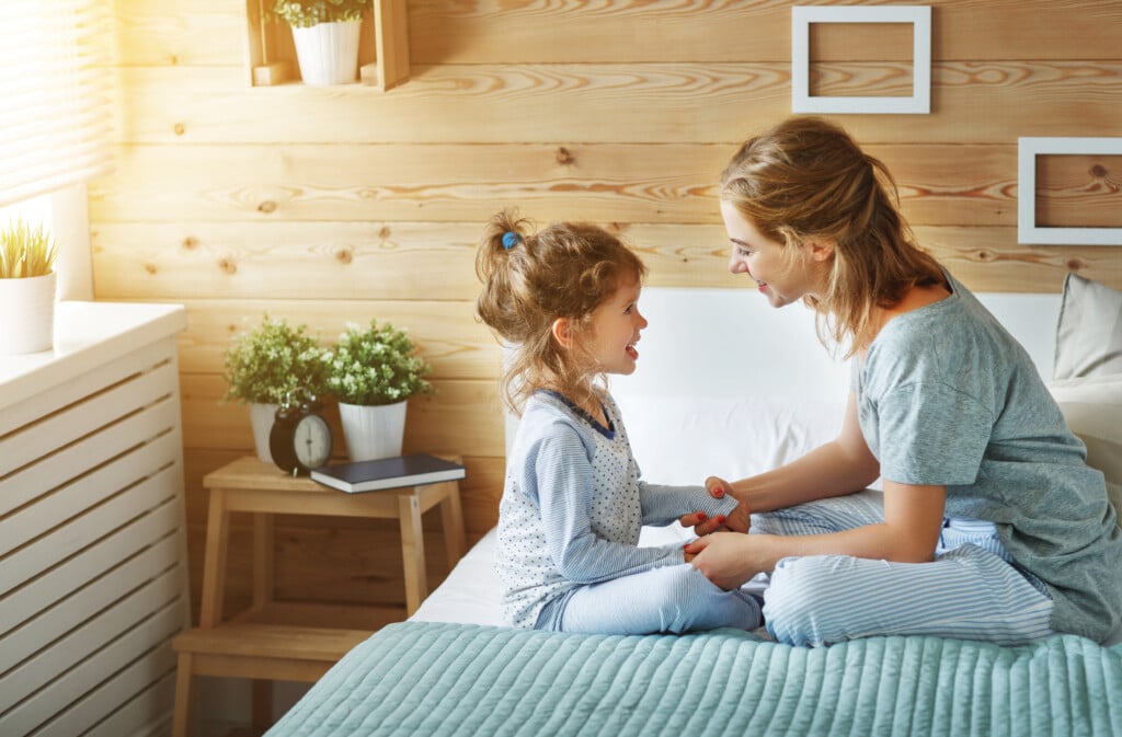 happy mother and child sitting on bed, for article on connecting with your child