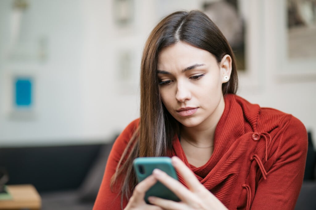 worried young woman looking at phone, for article on secret phone codes
