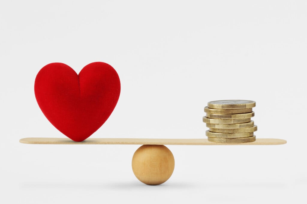 Scales balancing a heart and coins, for article on the marriage penalty for couples with disabilities