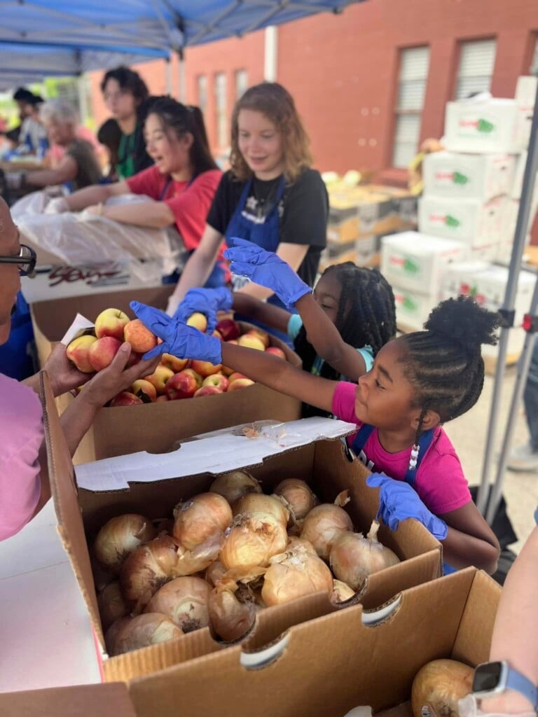 Kids at a table of fresh veggies at a Food On The Move Community Food and Resource Festival