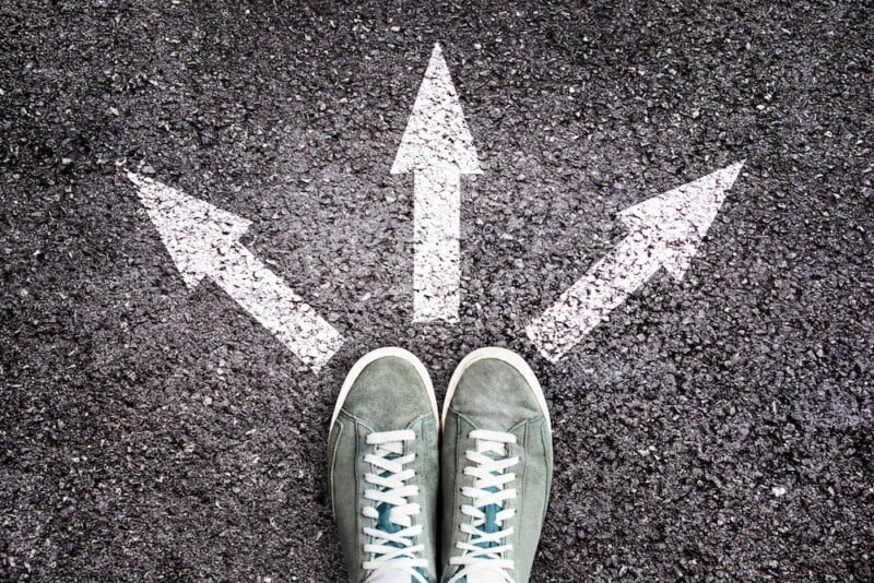 Shoes And Arrows Pointing In Different Directions On Asphalt Floor