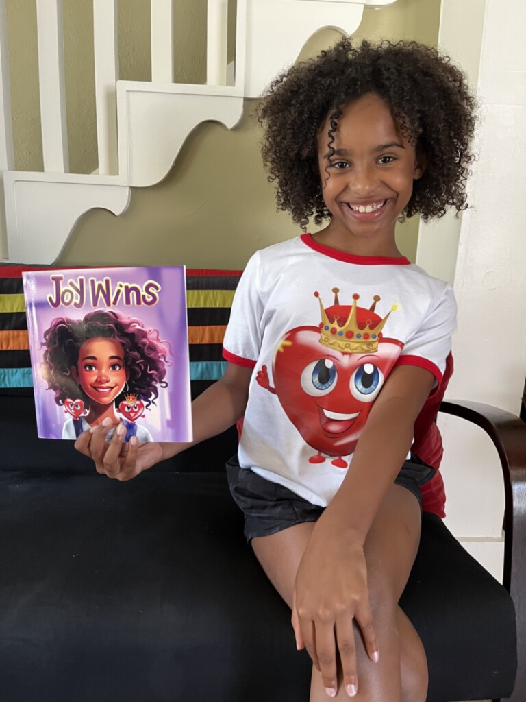 Zayalee Haynes holds a copy of her book, "Joy Wins"