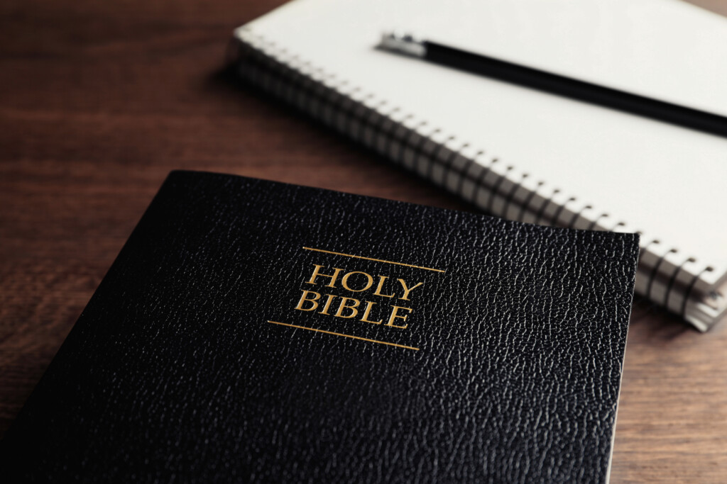 Bible and notebook and pencil on a wooden table