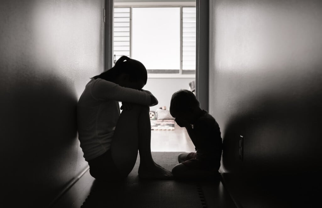 Sad Mother And Child Sitting On The Floor At Home.