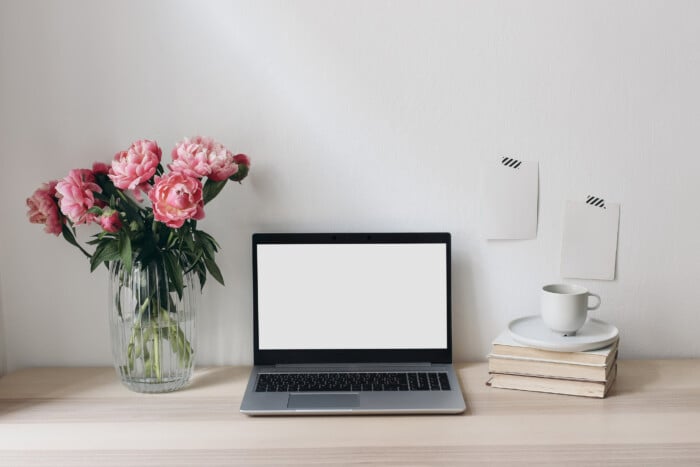 Home Office Still Life Scene. Notebook, Computer And Memo Cards Mock Ups. Vase With Pink Peonies Flowers, Books And Cup Of Coffee. Wooden Table. Elegant Feminine Working Space. Living Room Interior.