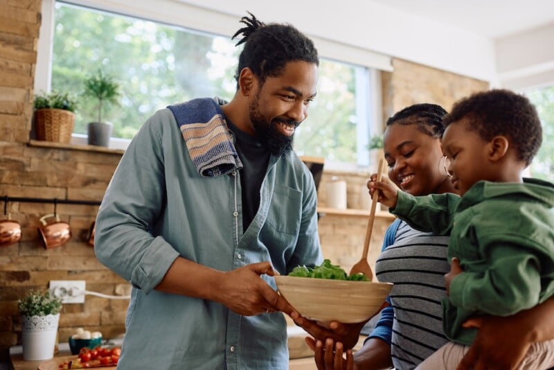 Father mom and young son holding a bowl of salad and smliling