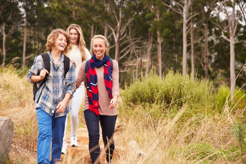 Happy Mother And Two Kids Hiking In A Forest