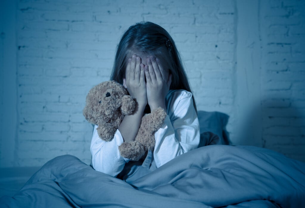 Scared Little Girl Sitting In Bed Covering Her Face