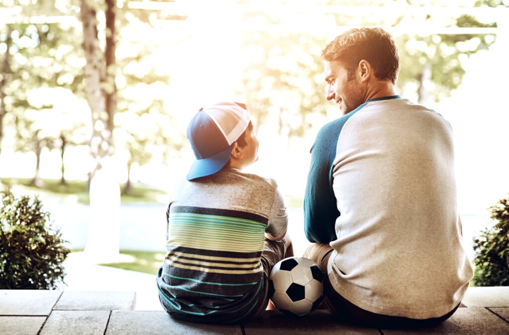father and son on porch with soccer ball between them